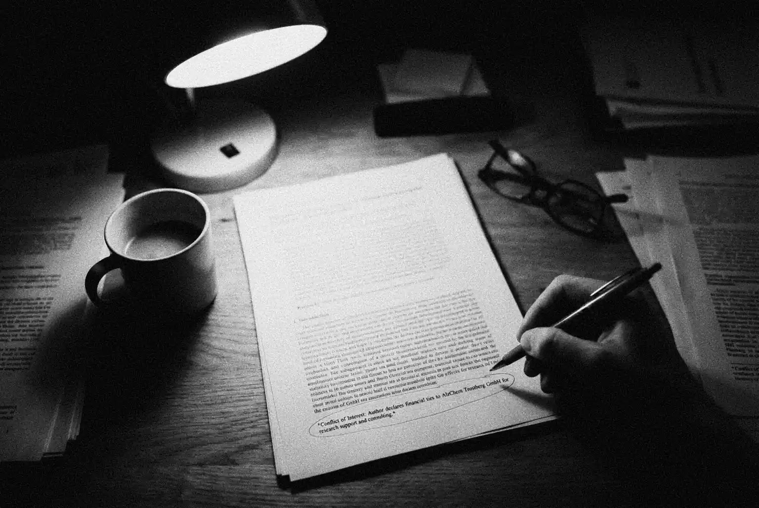 A high-angle shot of a dimly lit desk scattered with academic papers. A hand holding a pen has circled a footnote in a document that reads 'Conflict of Interest: Author declares financial ties to AlzChem Trostberg GmbH,' illustrating the centralised funding of creatine research.