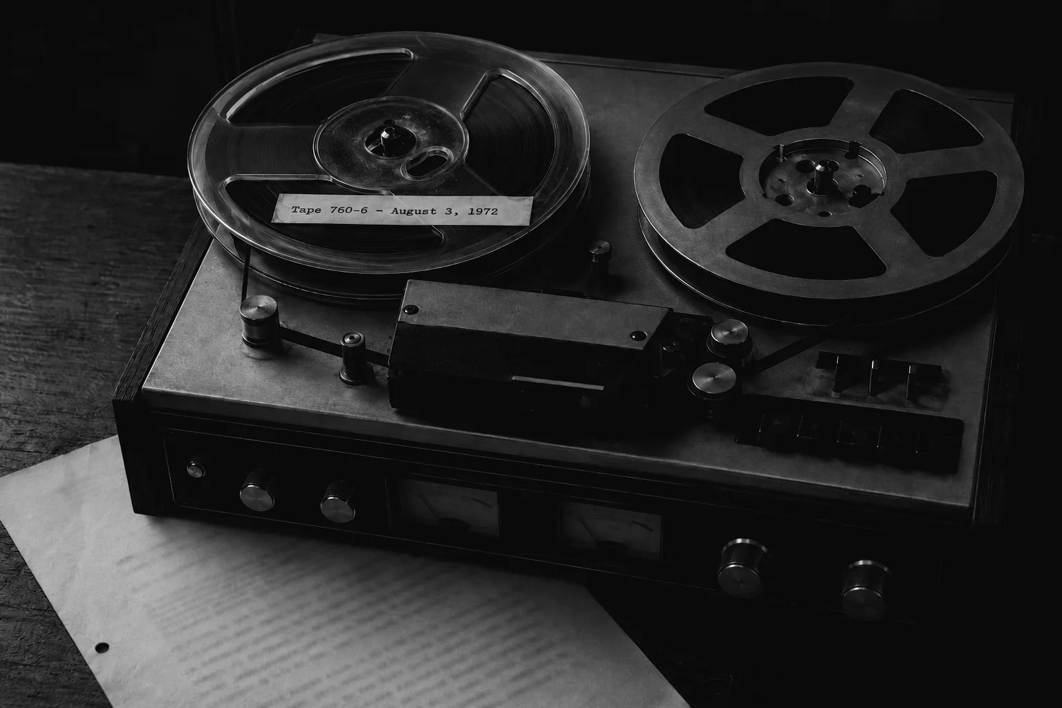 A close-up photograph of a 1970s reel-to-reel tape recorder with a label reading 'Tape 760-6 - August 3, 1972' resting above a declassified paper transcript from the Nixon administration.
